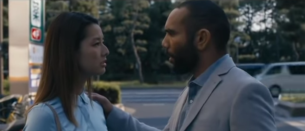 屋外で二人が話す、映画の一場面。